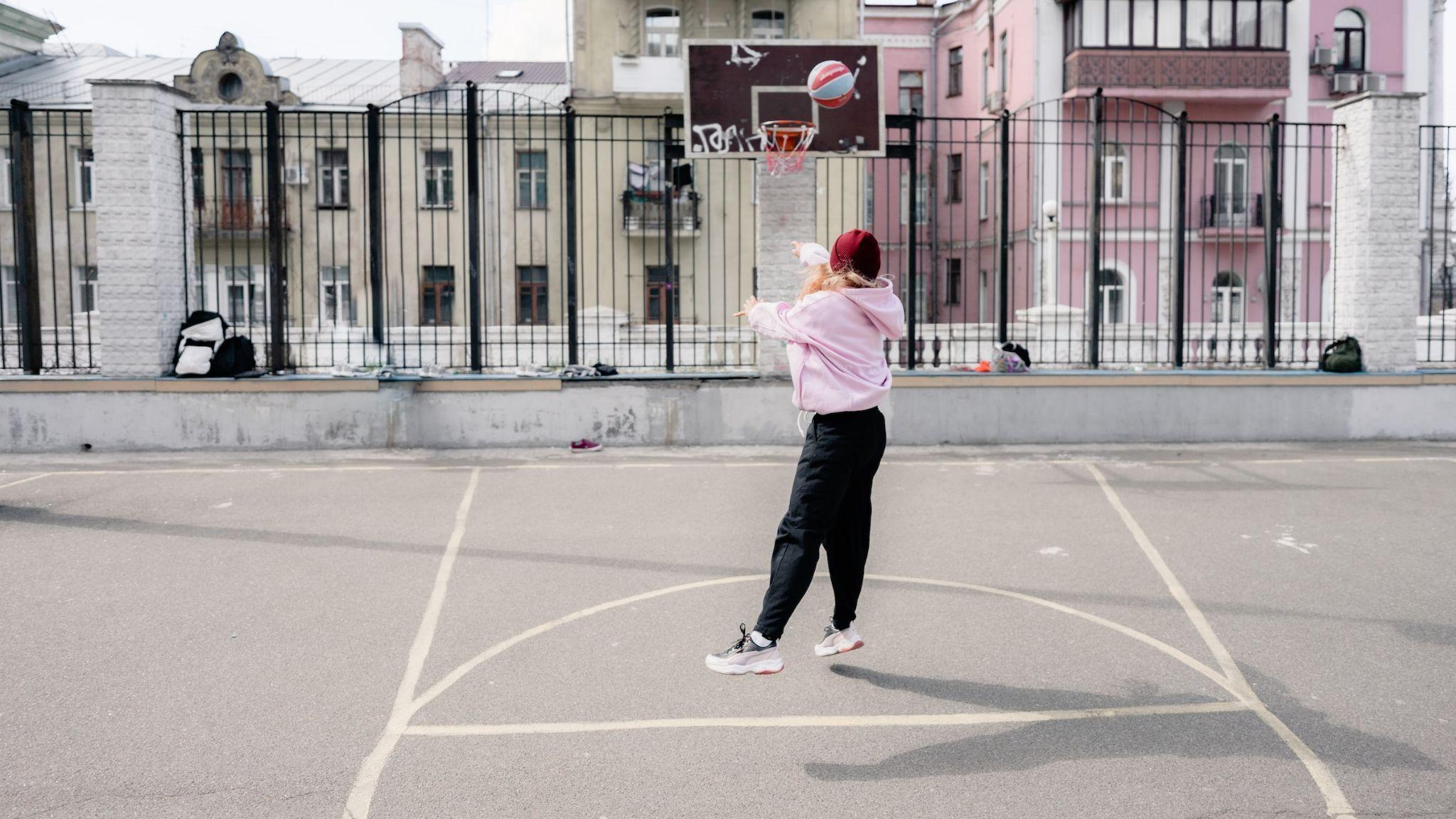 A Girl in Pink Hoodie Playing Basketball